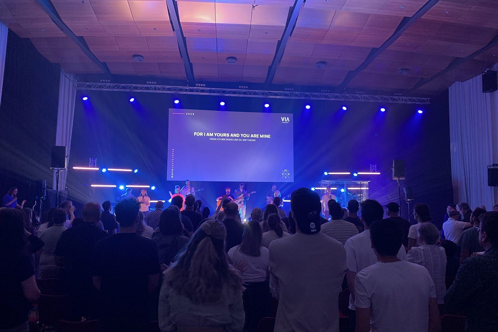 Konferenzsaal in blauer Lichtwäsche mit Band auf der Bühne